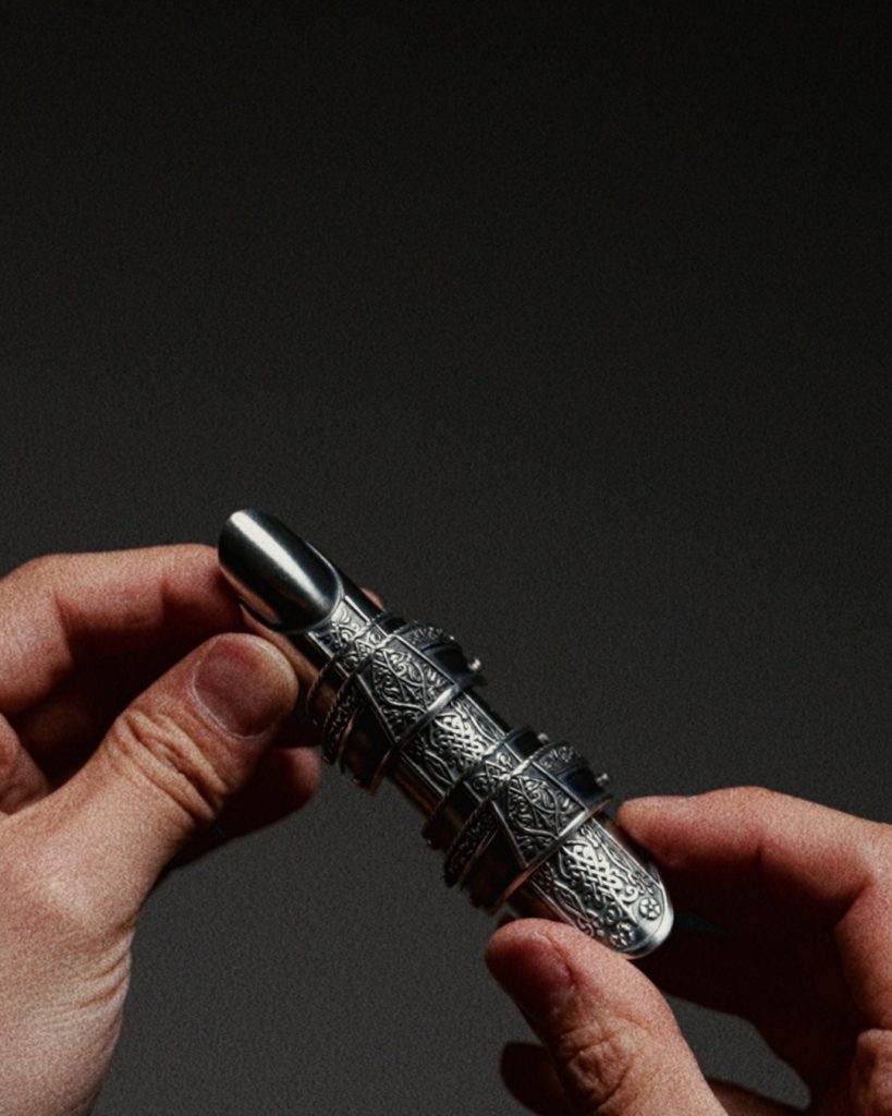 Finger armor de SHUWUU: extensiones metálicas articuladas para los dedos sosteniendo un encendedor